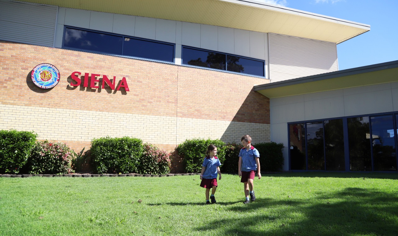 Students walking together on school grounds in front of the Siena building at St Bernardine’s School, highlighting a welcoming environment, friendship and everyday school life
